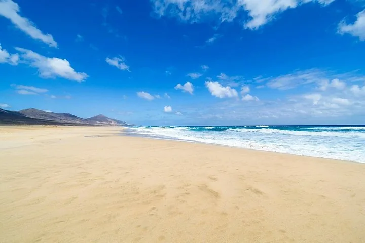 Ampia vista della spiaggia di Cofete con onde oceaniche e cielo azzurro limpido