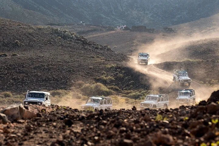 Convoi de Land Rover blancs roulant sur un sentier poussiéreux hors route