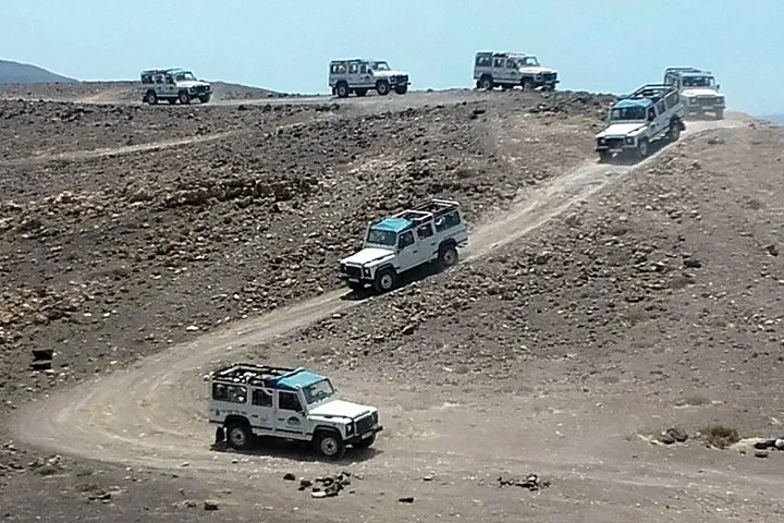 Several Land Rovers navigating an off-road terrain in a desert-like landscape