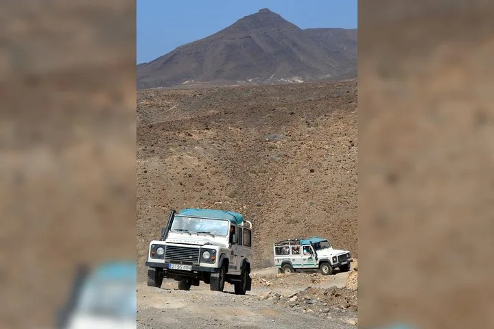 Land Rover auf einer Schotterstraße vor einer Bergkulisse